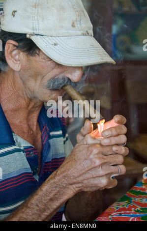 Vertical portrait of a Cuban man lighting a cigar. Stock Photo