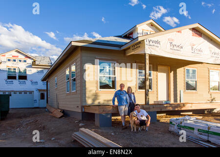 Family standing proudly in front of their new home under construction Stock Photo