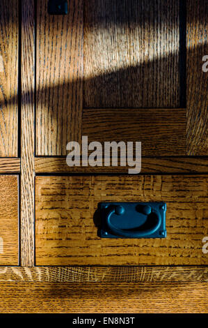 Late day sunlight streaming through a stained, leaded glass window creates interesting patterns on oak furniture. Stock Photo