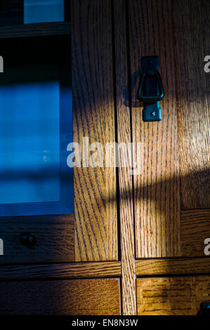 Late day sunlight streaming through a stained, leaded glass window creates interesting patterns on oak furniture. Stock Photo