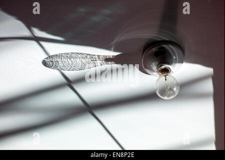 Early morning sun creates a shadow pattern from an incandescent lightbulb on a garage ceiling Stock Photo
