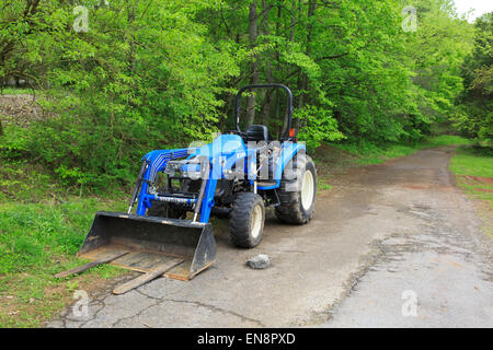 Blue Bush Hog TC400 tractor along a forest road Stock Photo