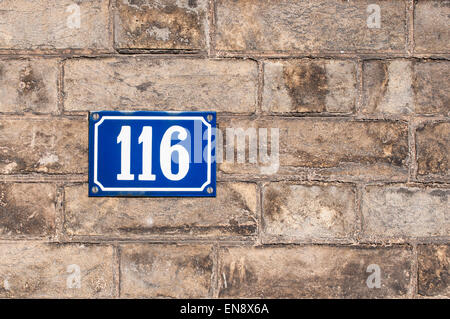House number one hundred and sixteen painted on metal plate on brick wall Stock Photo
