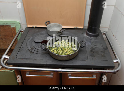 pot with cooked zucchini in the ancient stove with fire lit in the old mountain home Stock Photo