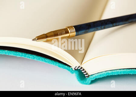 Open blank notebook with a pen on the note book page on a plain surface white background to illustrate keeping notes concept. Stock Photo
