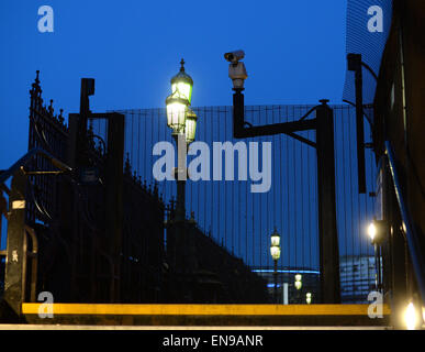 London, UK. 29th Apr, 2015. Streetlights and an observation camera behind fences on the Westminster Bridge close to the Palace of Westminster in the evening during the blue hour in London, England, 29 April 2015. Photo: Jens Kalaene/dpa/Alamy Live News Stock Photo