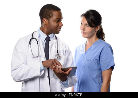 Two medical colleagues consulting a tablet-pc looking up patient records and charts with a handsome young African doctor in a wh Stock Photo