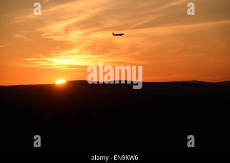 Jet plane approaching Glasgow international airport as the sun sets over the horizon in Scotland, UK Stock Photo