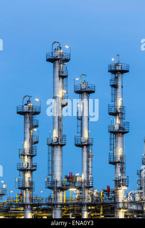 Detail of four distillation towers in a chemical plant and refinery with night blue sky. Stock Photo