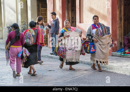 Tzotzil Indian women vendors walk on Real de Guadalupe carrying heavy  loads of hand loomed textiles for sale San Cristobal Stock Photo