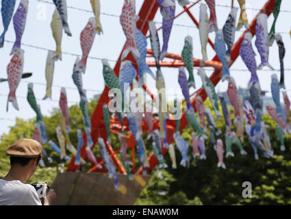 Tokyo, Japan. 1st May, 2015. A man takes photos of colorful carp streamers at Tokyo Tower ahead of the annual Boy Festival in Tokyo, Japan, May 1, 2015. Koinobori, or carp streamers, are displayed to celebrate Boy Festival on May 5 to wish boys to grow up as strong as the carp. Credit:  Stringer/Xinhua/Alamy Live News Stock Photo