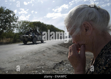 An elderly Georgian villager looks dejected as she watch Russian armoured personnel carriers on their way from Gori to the suburbs of Tbilisi during the Russo-Georgian War August 2008 Stock Photo