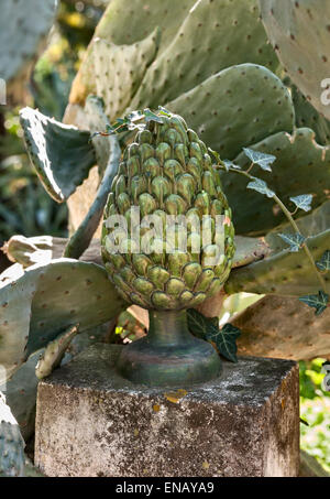 Villa Paterno, Catania, Sicily, Italy. Prickly pear cactus growing over a ceramic pineapple in a Sicilian garden