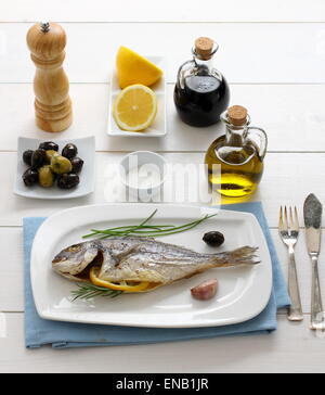 Garnished grilled sea bream with olives, lemon, top view Stock Photo