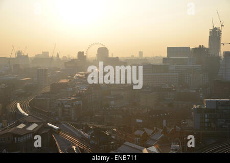 London skyline at dusk, the London Eye silhouetted and a train to London Bridge catches the golden hour sun Stock Photo