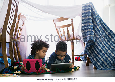Brother and sister using digital tablets in fort