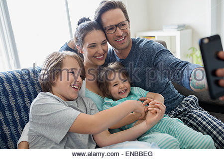 Family in pajamas taking selfie on sofa