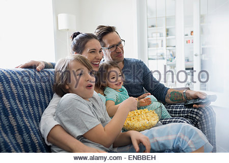 Family in pajamas watching TV and eating popcorn