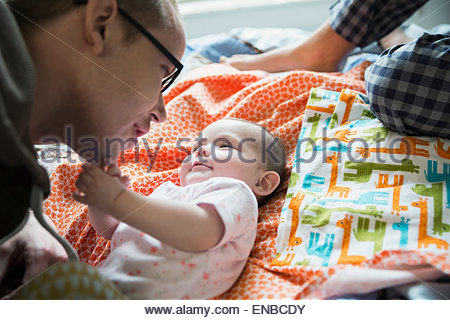 Father playing with baby daughter on bed