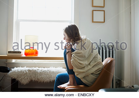Pensive woman looking out living room window