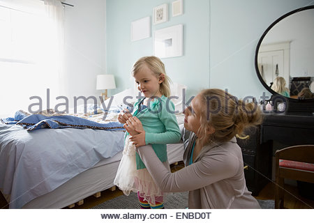 Mother dressing daughter in bedroom