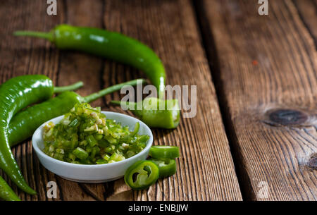 Green Chilis (cutted) on an old rustic wooden table Stock Photo