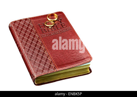Closed studio prop Bible cover with gold and diamond Wedding Rings isolated on white background Stock Photo