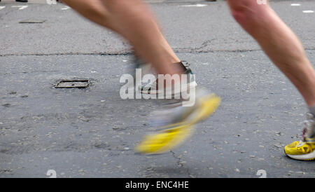 Detail of legs and yellow shoes of 2015 London Marathon competitors running along Upper Thames Street London UK KATHY DEWITT Stock Photo