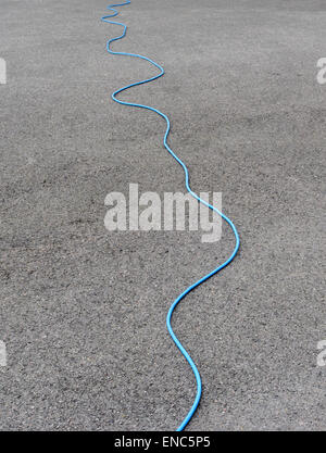 Long outdoor mains extension lead trailed across a driveway. Stock Photo