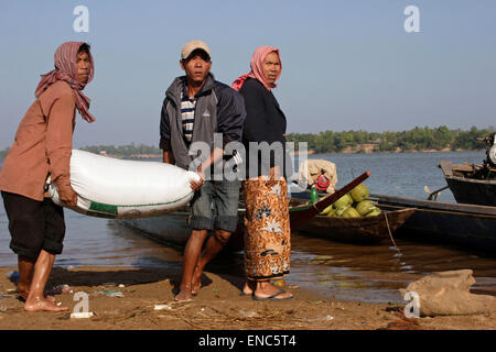 Two Khmer men unload a heavy sack of rice after arriving at the Stung Treng Pier in Stung Treng, Cambodia. Stock Photo