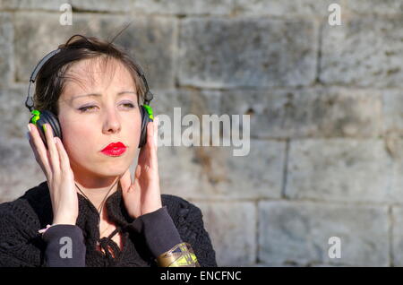 Pensive brunette listening to music on a headset outdoors Stock Photo