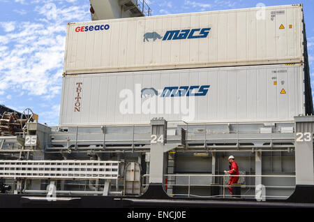 Seaman walking on a cargo vessel with containers in the background in the port of Cape Town, South Africa Stock Photo