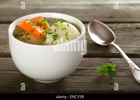 Traditional Chicken Soup with dumplings on a rustic wooden table with silver spoon Stock Photo
