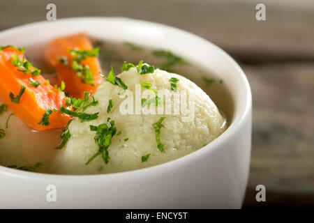 Close up of traditional chicken Soup with dumplings on a rustic wooden table