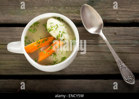 Traditional Chicken Soup with dumplings on a rustic wooden table with silver spoon Stock Photo