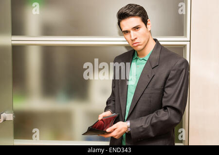 Sad looking young man showing empty wallet Stock Photo