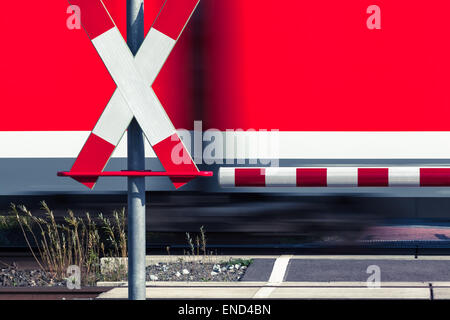 Railway crossing sign and a passing train Stock Photo