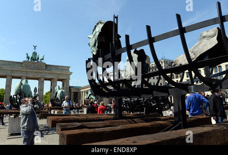 Berlin, Germany. 03rd May, 2015. Pedestrians examine the horse sculptures of the Mexcican artist Gustavo Aceves in front of the Brandenburg gate in Berlin, Germany, 03 May 2015. 'Lapidarium - overcoming borders' - under this motto the Mexican wants to refer back to the quadriga horse and carriage on the gate using archaelogical remains to build the sculptures. Photo: BRITTA PEDERSEN/dpa/Alamy Live News Stock Photo