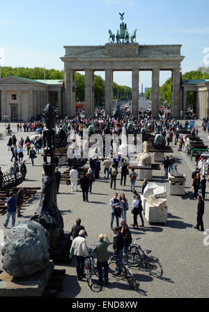 Berlin, Germany. 03rd May, 2015. Pedestrians examine the horse sculptures of the Mexcican artist Gustavo Aceves in front of the Brandenburg gate in Berlin, Germany, 03 May 2015. 'Lapidarium - overcoming borders' - under this motto the Mexican wants to refer back to the quadriga horse and carriage on the gate using archaelogical remains to build the sculptures. Photo: BRITTA PEDERSEN/dpa/Alamy Live News Stock Photo