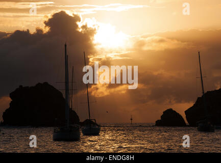 St. Barths, Saint-Barthélemy, French West Indies, French Antilles, Caribbean: rocks, cliffs and sailboats at sunset in the marina of Gustavia Stock Photo