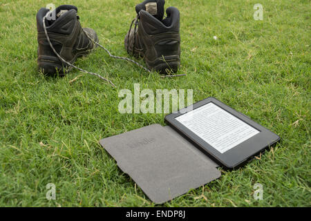 Amazon Kindle e-book reader on grass with hiking shoe near by Stock Photo
