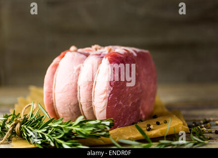 Organic pork lion roast with rosemary on wood farm table. Stock Photo