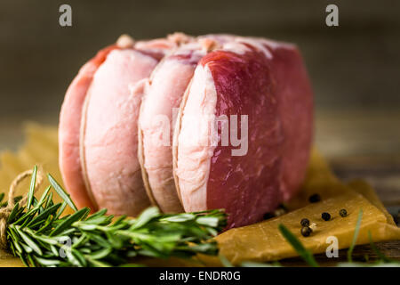 Organic pork lion roast with rosemary on wood farm table. Stock Photo