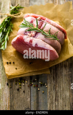 Organic pork lion roast with rosemary on wood farm table. Stock Photo