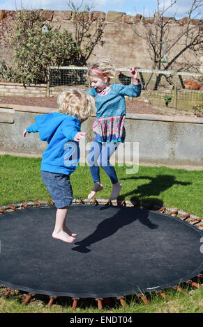 Brother and sister jumping on a trampoline Stock Photo