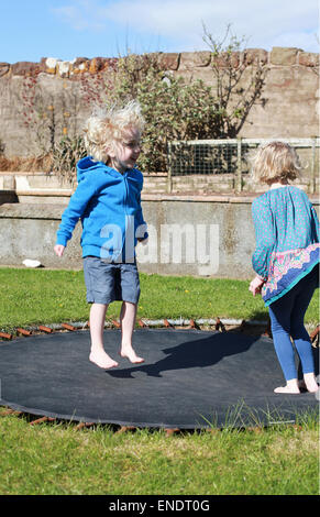 Brother and sister jumping on a trampoline Stock Photo