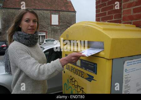 British expat, Julia White, 31, posts her postal vote in a French postbox. The vote must arrive by 10pm on 7th May 2015 to be co Stock Photo