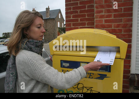 British expat, Julia White, 31, posts her postal vote in a French postbox. The vote must arrive by 10pm on 7th May 2015 to be co Stock Photo