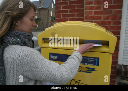 British expat, Julia White, 31, posts her postal vote in a French postbox. The vote must arrive by 10pm on 7th May 2015. Stock Photo