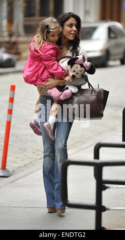 Bethenny Frankel, wearing bell bottom jeans and carrying a Prada bag